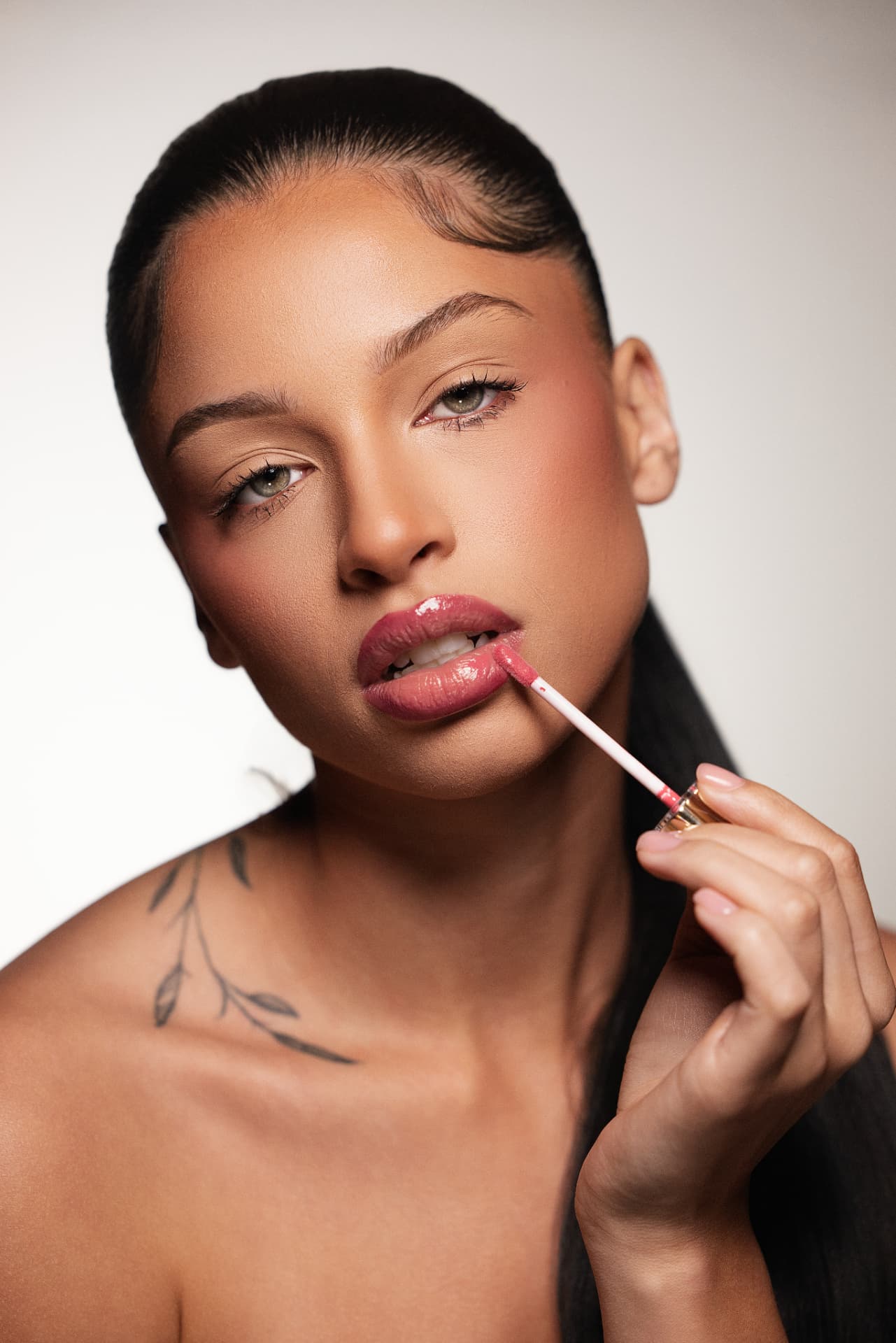 Model applying Thee Rich Girls lip gloss