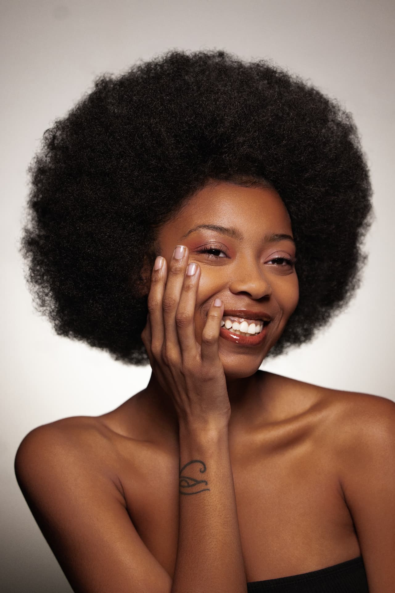 Model smiling in a warm Thee Rich Girls lip shade